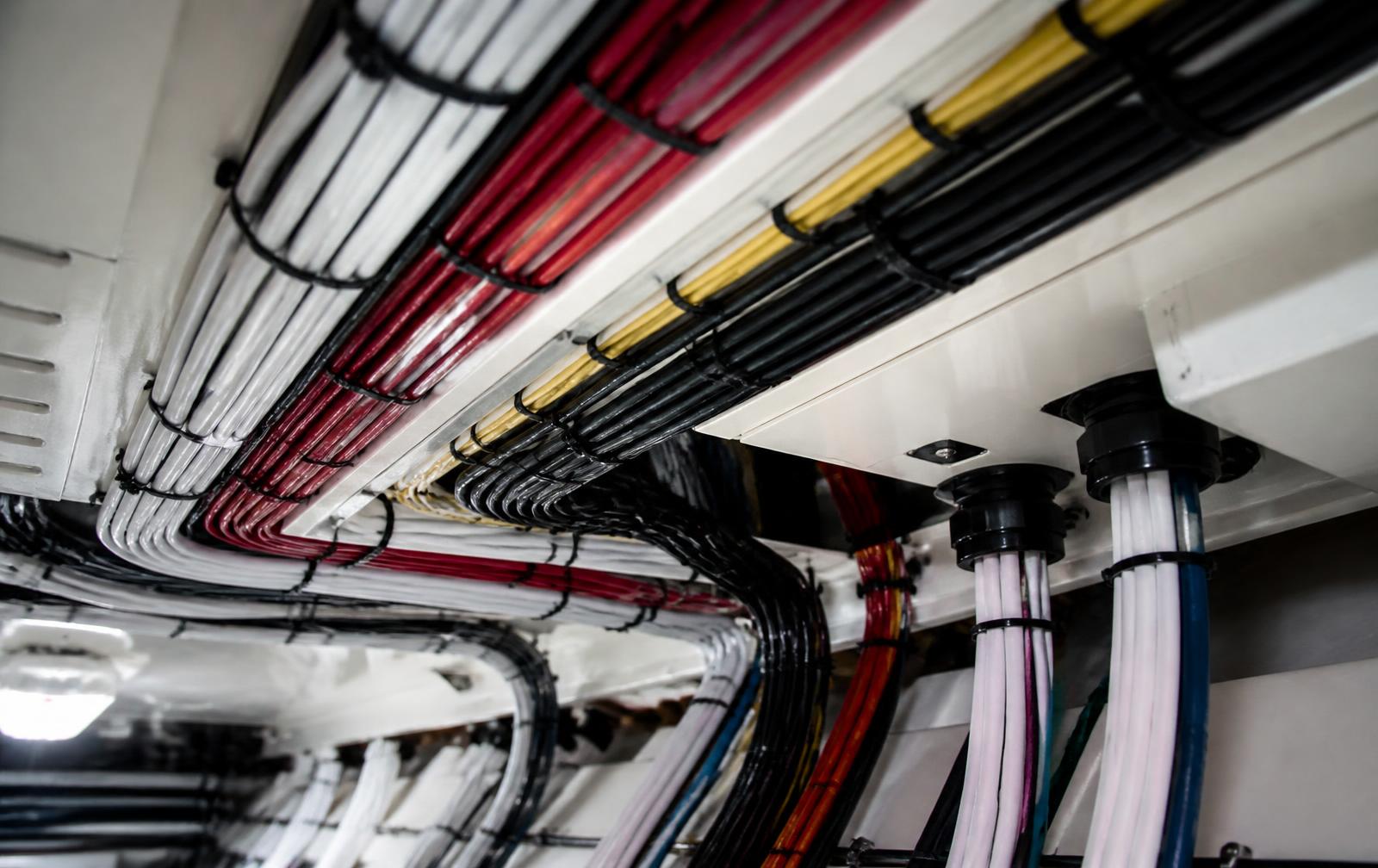 Neatly loomed and supported marine wiring bundles routed through a yacht overhead void