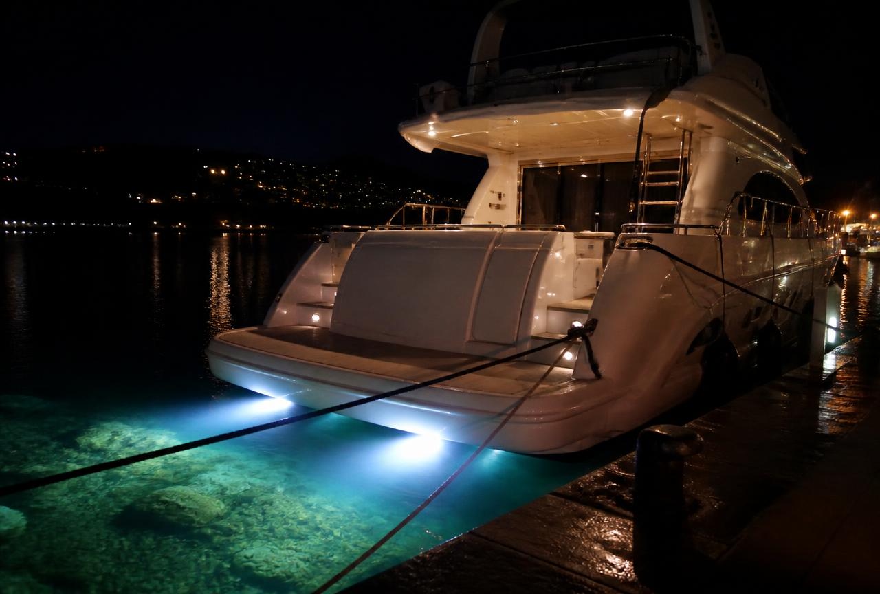 Motor yacht at night with underwater lights glowing beneath the transom